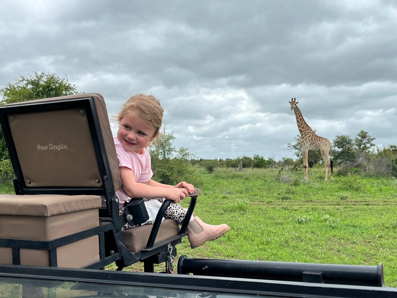 Anthony's granddaughter in the tracker seat next to a giraffe